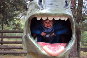 Bild: Kind sitzt in einem Dinosauriermaul und guckt heraus