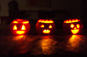 Bild: drei leuchtende Kürbisköpfe mit Gesicht auf dem Boden