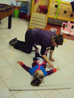 Bild: Kind leigt auf einem großen Papierbogen auf dem Rücken auf dem Fußboden und Erwachsener umzeichnet die Umrisse