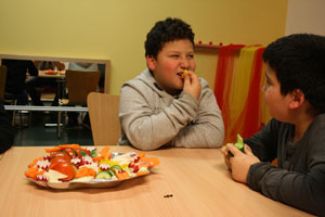 Bild: zwei dicke Jungs beim essen von Gemüse am Tisch sitzend